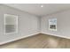 Empty bedroom showcasing light hardwood floors, neutral paint, white trim, and two large windows at 104 Wilderness Ct, Mebane, NC 27302