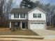 Two-story home featuring stone accents, a two-car garage, black shutters, and a well-manicured lawn at 104 Wilderness Ct, Mebane, NC 27302