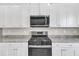 Close up view of the oven and microwave, granite countertops, and white cabinets at 104 Wilderness Ct, Mebane, NC 27302