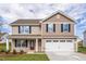 Charming two-story home featuring stone accents, a two-car garage, and a welcoming front porch at 109 Wilderness Ct, Mebane, NC 27302