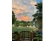 Picturesque backyard view featuring a tranquil pond reflecting a sunset, palm trees, and a wooden deck with plants at 123 Glasgow Dr, Clayton, NC 27520