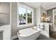 Bright bathroom with a soaking tub, modern fixtures, and a large window offering beautiful outdoor views at 1600 Sweetwater Ln, Raleigh, NC 27610
