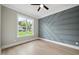 Bright bedroom with modern accent wall, ceiling fan, hardwood floors and large window at 1600 Sweetwater Ln, Raleigh, NC 27610