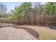 Landscaped backyard with trees, shrubbery, and brick paver patio at 1680 Mint River Dr, Apex, NC 27502