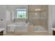 Bathroom showcasing a soaking tub, a glass-enclosed shower, and a bright window at 1680 Mint River Dr, Apex, NC 27502