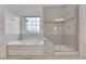 Bright bathroom with a soaking tub, a tiled shower, and a large window with natural light at 1680 Mint River Dr, Apex, NC 27502