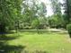 A single-story home surrounded by a lush green lawn and mature trees at 2118 Timberlake Dr, Raleigh, NC 27604