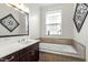 Modern bathroom with a soaking tub, single sink, marble countertop, and dark cabinets at 2675 Beckwith Rd, Apex, NC 27523