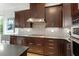 Close up of kitchen with dark cabinets, gas range and stylish backsplash with range hood at 2675 Beckwith Rd, Apex, NC 27523