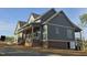 View of the side of the home with vertical siding, brick foundation, covered deck, and professionally landscaped yard at 2833 Faucette Ln, Burlington, NC 27217