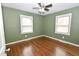 Bedroom featuring hardwood floors, a ceiling fan, and two windows with natural light at 300 W Carr St, Mebane, NC 27302