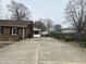 Long driveway leading to brick home with well maintained yard and mature trees, offering curb appeal at 300 W Carr St, Mebane, NC 27302