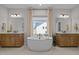 Elegant bathroom with dual vanities, stylish light fixtures, and freestanding tub in front of a window at 3215 Jones Lake Rd, Fuquay Varina, NC 27526