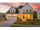 Stunning two-story home featuring a 2-car garage, lush landscaping, and a welcoming front porch with elegant lighting at 3215 Jones Lake Rd, Fuquay Varina, NC 27526