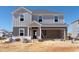 Two-story home showing gray vertical siding, open garage, and front porch under construction at 3401 Rosebush Dr, Zebulon, NC 27597