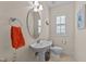Elegant powder room with pedestal sink, oval mirror, and a window offering natural light at 5213 Orabelle Ct, Raleigh, NC 27606