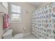 Well-lit bathroom featuring a window, toilet, and a shower with a vibrant bird-themed curtain at 5213 Orabelle Ct, Raleigh, NC 27606