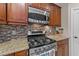 Close-up of a stainless steel gas range with a microwave and tile backsplash in the kitchen at 5213 Orabelle Ct, Raleigh, NC 27606