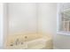 Relaxing soaking tub next to a window offering natural light in the bathroom at 604 S Chavis St, Franklinton, NC 27525