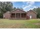 Rear view of the brick house featuring a covered porch, steps, and landscaped yard at 604 S Chavis St, Franklinton, NC 27525
