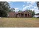 Rear view of a brick house with a covered porch, a well-maintained lawn, and mature trees providing shade at 604 S Chavis St, Franklinton, NC 27525