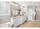 Bright bathroom with a double vanity, granite countertop, decorative mirror, and a tiled walk-in shower at 7001 Millstone Ridge Ct, Raleigh, NC 27614