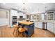 Bright eat-in kitchen with white cabinets, stainless appliances, wood island with seating, and hardwood floors at 7001 Millstone Ridge Ct, Raleigh, NC 27614