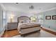 This is a primary bedroom with hardwood floors, panel molding, a crystal light fixture and light blue walls at 712 Tarleton Ave, Burlington, NC 27215