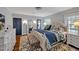 Cozy bedroom features blue accent wall, decorative bed, white dresser, gray ottoman, hardwood floors and two blue doors at 712 Tarleton Ave, Burlington, NC 27215