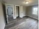 Bedroom view showcasing hardwood floors, closet, and attached room with stainless refrigerator at 804 S Sampson Ave, Dunn, NC 28334