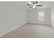 A comfortable bedroom with neutral carpet, ceiling fan, a window, and a white door at 100 Lexington Ave, Zebulon, NC 27597