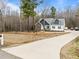 Exterior shot showcasing the house, its large front yard, and long driveway leading to the residence at 100 Lexington Ave, Zebulon, NC 27597