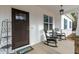 Covered porch with rocking chairs, stylish light fixture and welcoming door, enhancing curb appeal at 100 Lexington Ave, Zebulon, NC 27597