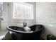 Bright bathroom showcasing a luxurious soaking tub beneath a window, complemented by elegant marble tile at 1012 Casa Dega Way, Raleigh, NC 27613