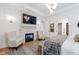 A well-appointed bedroom features a stone fireplace and a flatscreen television with two chairs in front of the bed at 1012 Casa Dega Way, Raleigh, NC 27613