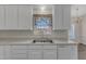 The modern kitchen is filled with white cabinets, a large window, and a stainless steel sink at 103 Fieldstone Dr, Clayton, NC 27520