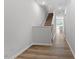 Hallway featuring wood-look flooring, stairs with white banisters, and gray walls at 116 Central Townes Way # 293, Raleigh, NC 27603