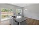 Bright kitchen island with stainless sink, gray granite countertops, white cabinetry, and hardwood floors at 116 Central Townes Way # 293, Raleigh, NC 27603