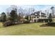 Expansive backyard featuring a lush lawn, manicured landscaping, pool, and a traditional-style home with multiple chimneys at 12132 Lockhart Ln, Raleigh, NC 27614