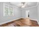 Bright bedroom with hardwood floors, a ceiling fan, and a large window showcasing outdoor views at 12132 Lockhart Ln, Raleigh, NC 27614