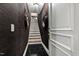Elegant staircase with hardwood steps, dark wall coverings, leading upwards, and black and white tile at 12132 Lockhart Ln, Raleigh, NC 27614