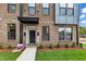 Modern townhome exterior featuring brick facade, black door, manicured lawn, and covered entryway at 1257 S Blount Street # 101, Raleigh, NC 27601