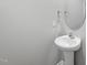 A minimalist bathroom design with a white pedestal sink, round mirror, and neutral wall color at 147 Young Farm Dr, Lillington, NC 27546