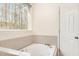 Bright bathroom features a tiled deck bathtub next to a window view and a white door at 1532 Rockwood Downs Dr, Wendell, NC 27591