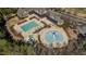 Aerial view of the pool area, featuring a large swimming pool and a splash pad, surrounded by trees and a clubhouse at 1637 Hasentree Villa Ln, Wake Forest, NC 27587