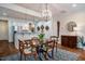 Cozy dining area with a wooden table set and a modern chandelier, adjacent to the kitchen with stainless steel appliances at 211 Monarda Way, Hillsborough, NC 27278