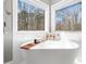 Luxurious bathroom featuring a soaking tub with wooden tray and scenic views at 2309 Laurelford Ln, Wake Forest, NC 27587