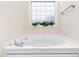 Corner bathtub with chrome faucet and decorative plants at 2639 Bowden Dr, Creedmoor, NC 27522