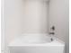 A clean white bathtub awaits in this bathroom with tile walls and a sleek, modern faucet and showerhead at 325 Azalea Gaze Dr, Youngsville, NC 27596