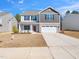 Two-story home featuring a two-car garage, stone accents, and well-maintained lawn at 325 Azalea Gaze Dr, Youngsville, NC 27596